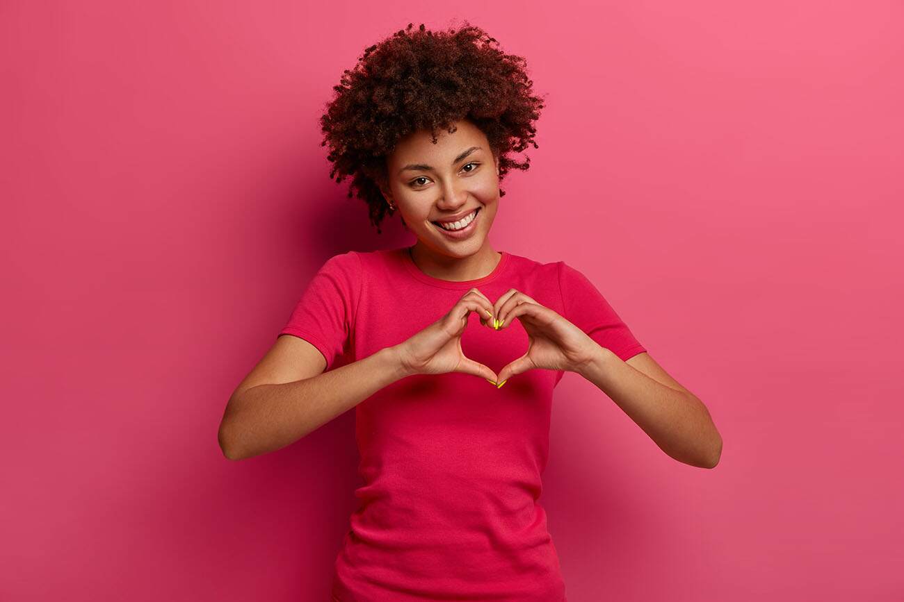 Pretty Curly American Paid Clinical Trial Participant Making a Heart Sighn With Her Hands