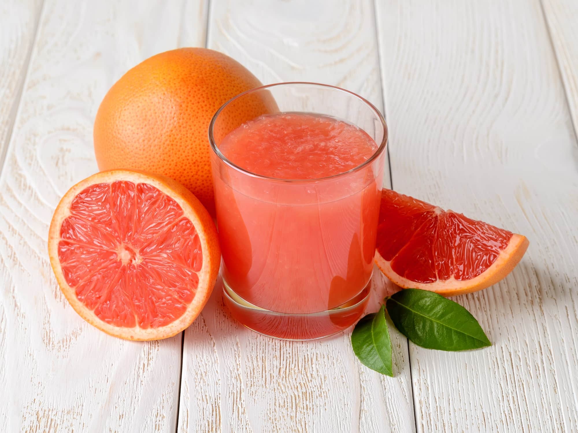 Grapefruit juice glass with some grapefruit around the glass.
