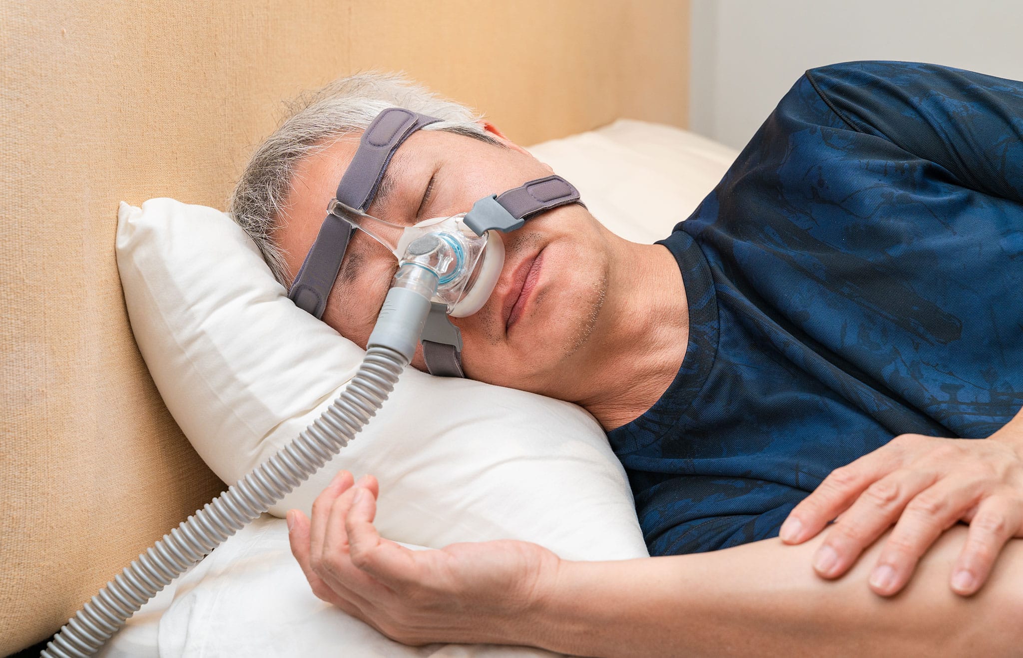 Middle age clinical trial participant wearing CPAP headgear during his sleep.