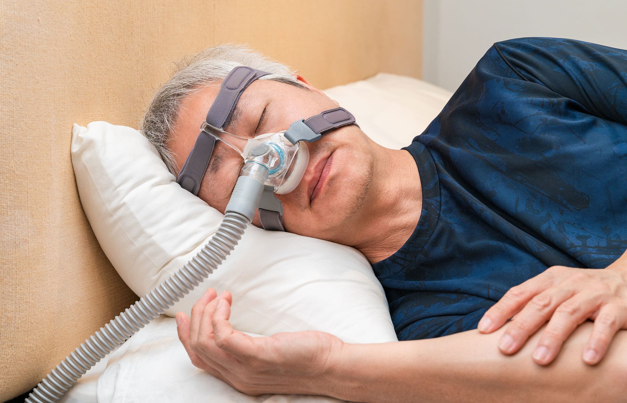 Middle age Asian man wearing CPAP headgear during his sleep