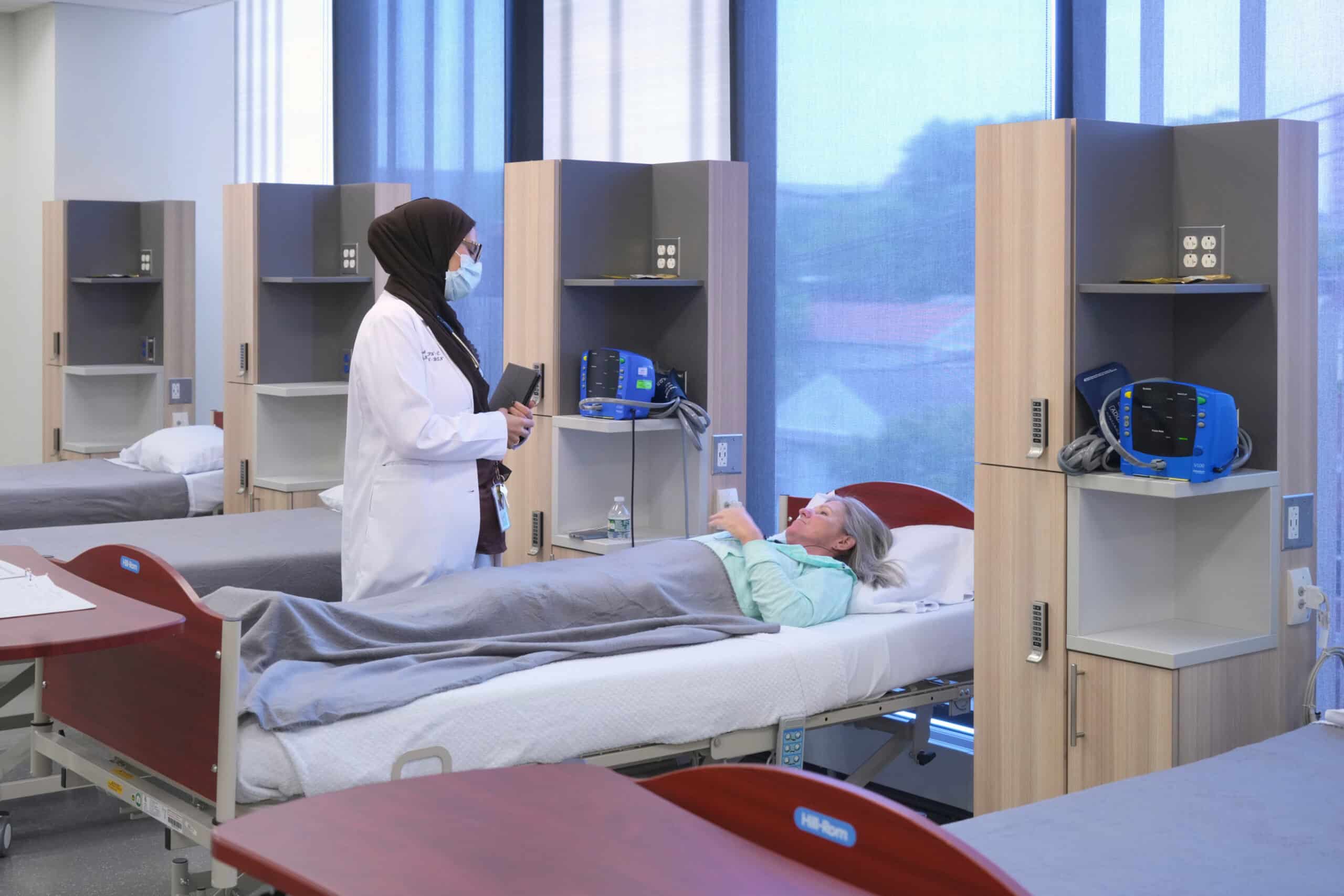 Paid Clinical Trial participant laying on the bed and talking to a nurse standing beside the bed.
