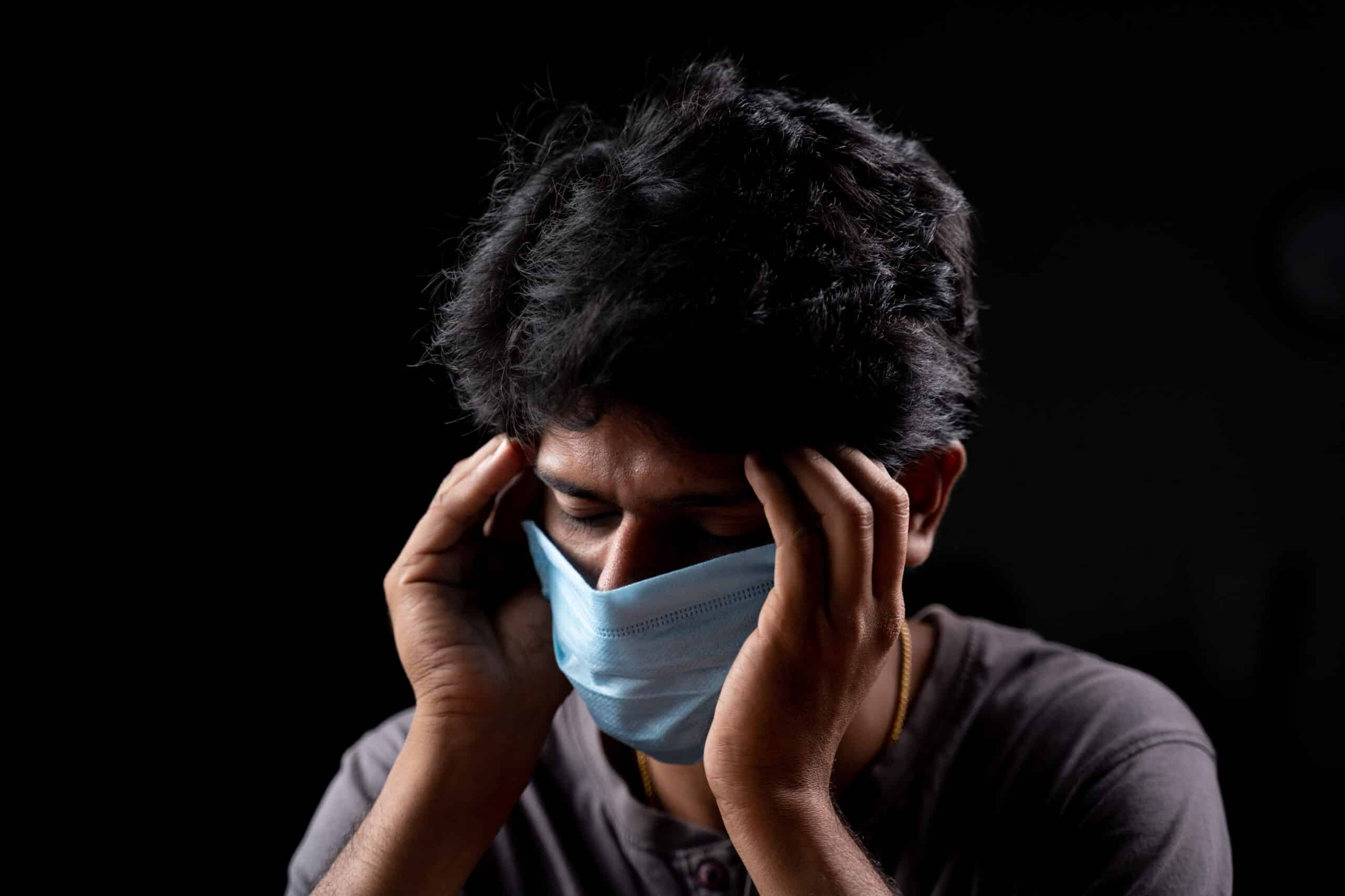 Young Man With Medical Mask Holding His Head