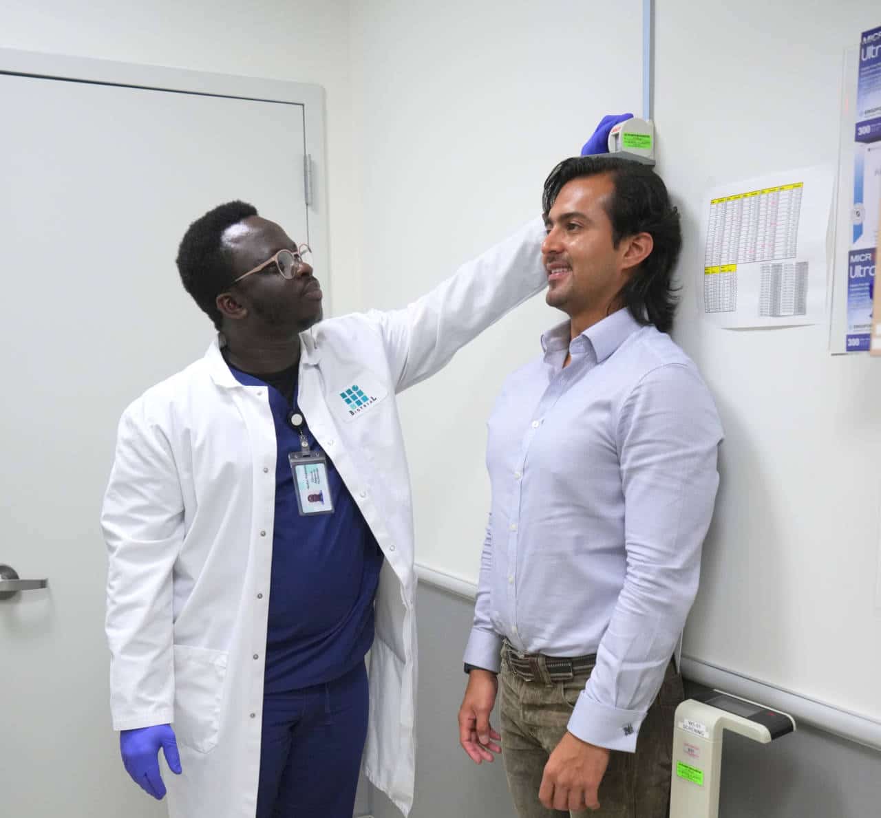 Biotrial researcher measuring height of a male clinical trial participant.